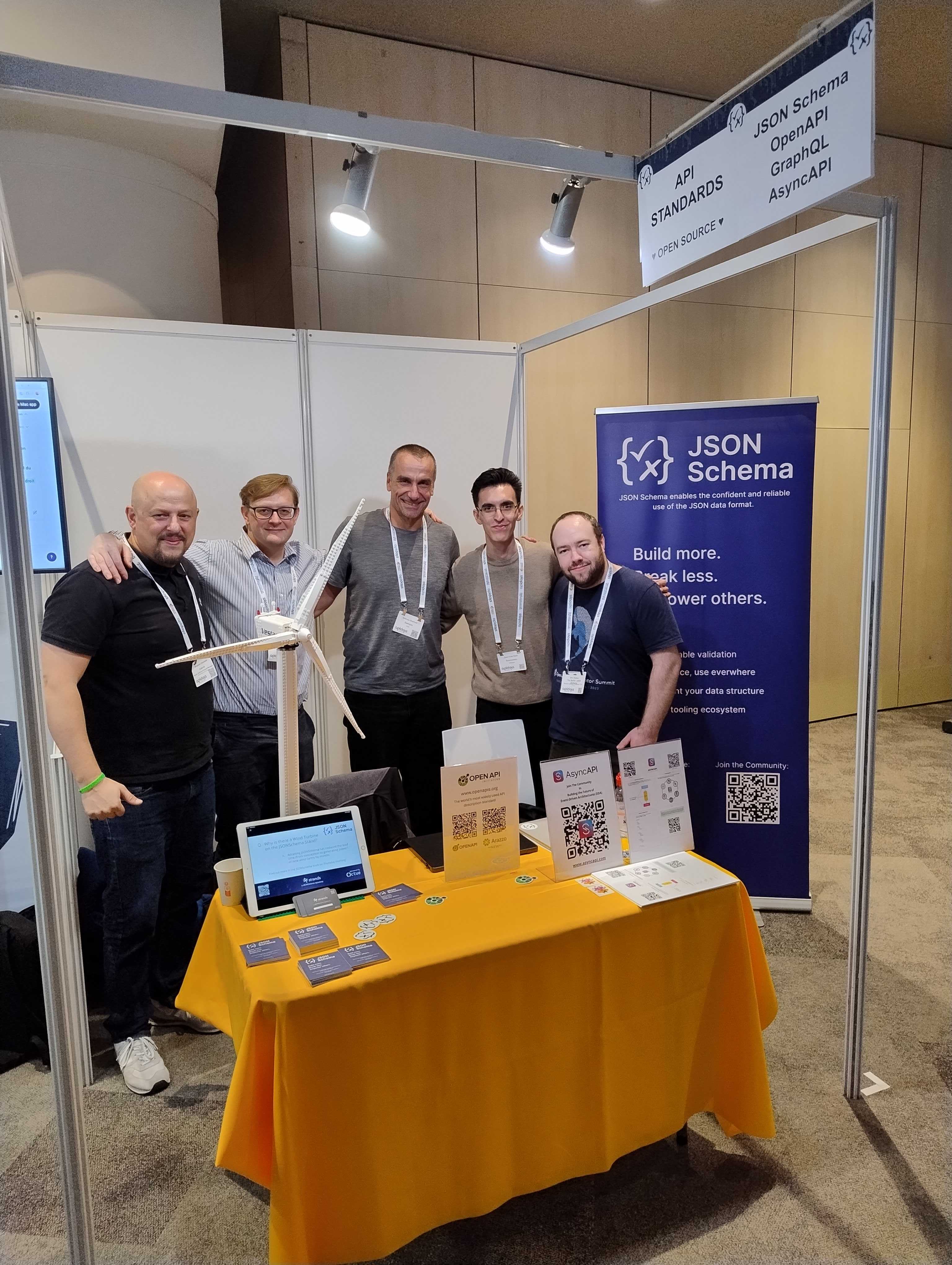 Five people standing at a booth labeled 'Standards'. They are smiling and looking at the camera. From left to right, their names are Benja Granados, Thomas Clark, Andreas Eberhart, Juan Cruz Viotti, and Ben Hutton.